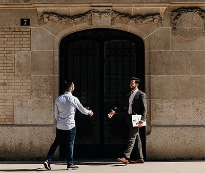 Rencontre entre un agent immobilier et un client devant un bâtiment haussmannien